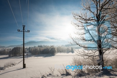 Austrian Winter Wonderland With Mountains, A Power Pole In Fresh Snow And Haze Stock Photo