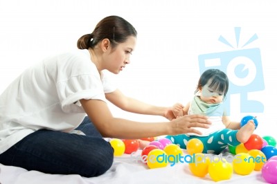 Baby Girl Is Playing Ball With Her Mother On White Background Stock Photo