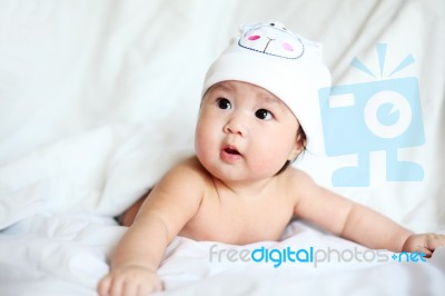 Baby With Cow Hat Lying Down On A White Blanket Stock Photo