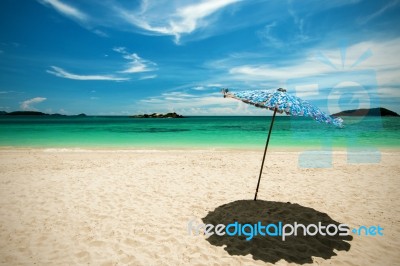 Beach Umbrella With Emerald Sea On A Sunny Day, Island In Background, Thailand Stock Photo