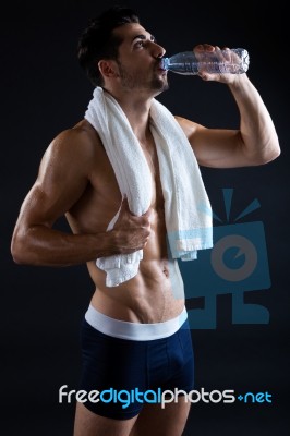 Beautiful And Muscular Man Drinking Water In Dark Background Stock Photo
