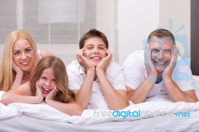 Beautiful Family Lying On Bed Smiling And Looking At You Stock Photo
