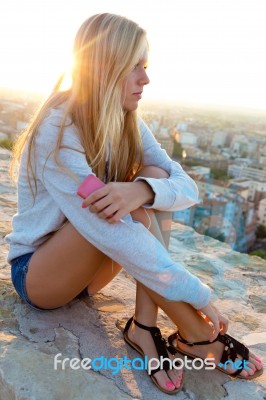 Beautiful Girl Sitting On The Roof And Listening To Music Stock Photo