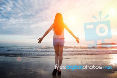 Beautiful Girl Walking On The Beach At Sunset Stock Photo