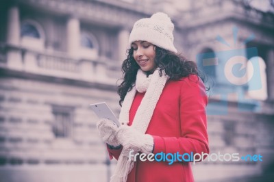 Beautiful Woman In Red Coat And Wool Cap And Gloves With Smartph… Stock Photo