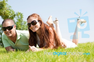Beautiful Young Couple Lie Down On Grass Stock Photo