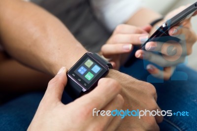 Beautiful Young Couple Using A Smartwatch At Home Stock Photo