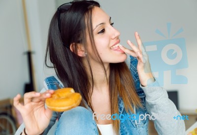 Beautiful Young Woman Eating Donuts At Home Stock Photo