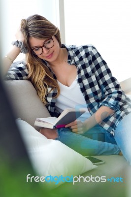 Beautiful Young Woman Reading A Book In The Sofa Stock Photo