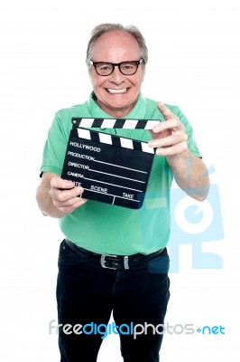 Bespectacled Elderly Man Holding A Clapperboard Stock Photo