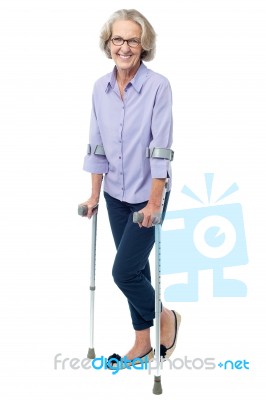 Bespectacled Old Woman Walking With Crutches Stock Photo