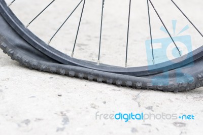 Bicycle Wheel With Flat Tyre On The Concrete Road Stock Photo