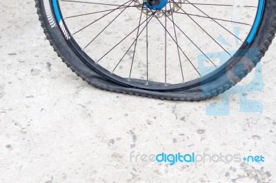 Bicycle Wheel With Flat Tyre On The Concrete Road Stock Photo