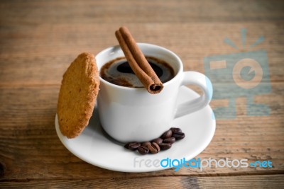 Black Coffee In White Cup With Biscuit And Cinnamon Stick Stock Photo