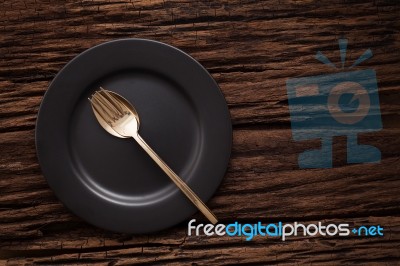 Black Empty Plate Fork Spoon On Wooden Table Background Stock Photo