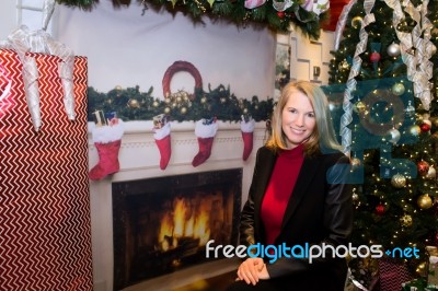 Blonde Female Sitting Next To Christmas Tree And Large Gift Stock Photo