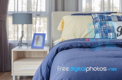 Blue Picture Frame With Modern Lamp On Wooden Side Table Stock Photo