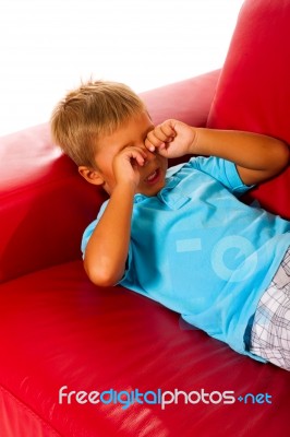 Boy Lying And Rubbing His Eyes Stock Photo