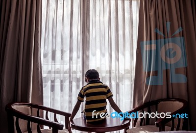 Boy Sitting On A Table Looking Down Down Stock Photo