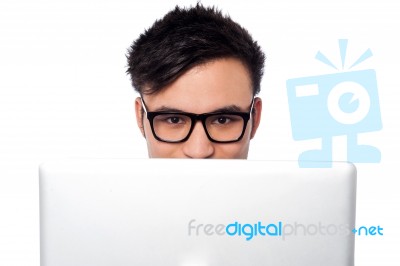 Boy Trying To Hide His Face Behind Laptop Stock Photo