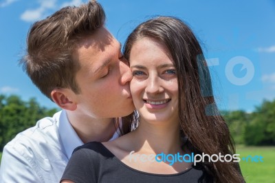 Boyfriend Kisses Girlfriend On Cheek In Sunny Nature Stock Photo