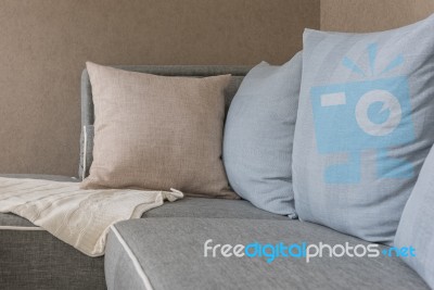 Brown And Blue Pillows With Blanket On Modern Grey Sofa Stock Photo