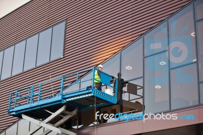 Builder On A Scissor Lift Platform At A Construction Site Stock Photo