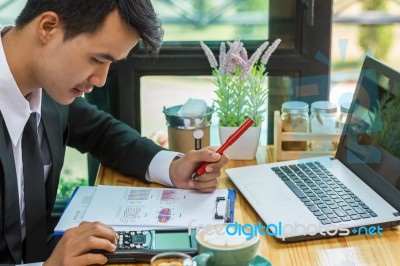 Business Man Sitting On A Calculator To Figure Out In A Coffee S… Stock Photo