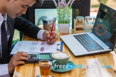 Business Man Sitting On A Calculator To Figure Out In A Coffee S… Stock Photo