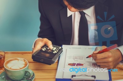 Business Man Sitting On A Calculator To Figure Out In A Coffee S… Stock Photo Business Man Sitting On A Calculator To Figure Out In A Coffee S… Stock Photo