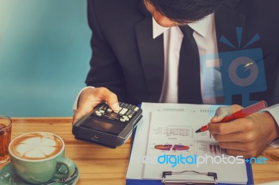 Business Man Sitting On A Calculator To Figure Out In A Coffee S… Stock Photo