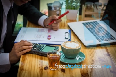 Business Man Sitting On A Calculator To Figure Out In A Coffee S… Stock Photo