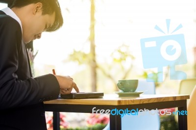 Business Man Sitting On A Calculator To Figure Out In A Coffee S… Stock Photo