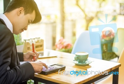 Business Man Sitting On A Calculator To Figure Out In A Coffee S… Stock Photo