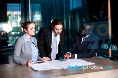 Business Team Of Three Reviewing Project Plan Stock Photo