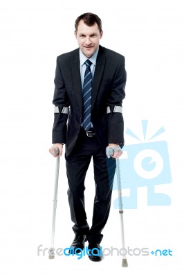 Businessman Walking With Crutches Stock Photo