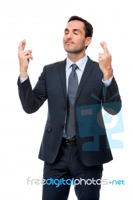 Businessman With Eyes Closed And Fingers Crossed Stock Photo