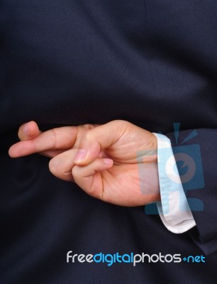 Businessman With Fingers Crossed Stock Photo