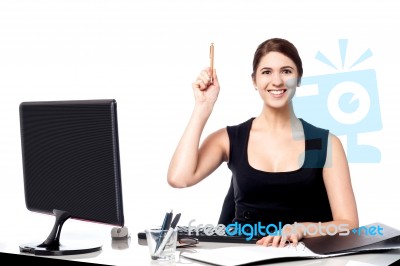 Businesswoman Holding Pen And Raising Her Hand Stock Photo
