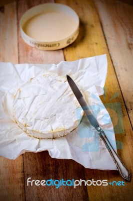Camembert Cheese Wrapped In Paper With Vintage Knife On Wooden T… Stock Photo