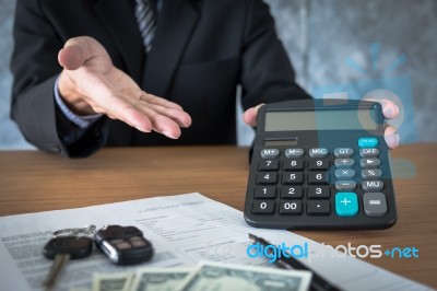 Car Salesman Holding A Key And Calculating A Price At The Dealer… Stock Photo