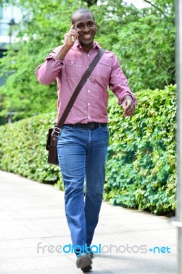 Casual Man Talking On The Phone While Walking Stock Photo