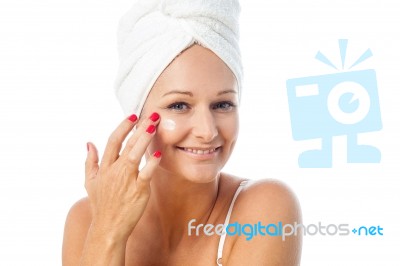 Charming Woman Applying Lotion On Her Face Stock Photo