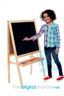 Charming Young Girl Writing On Blackboard Stock Photo