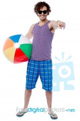 Cheerful Guy With Beach Ball Pointing At You Stock Photo