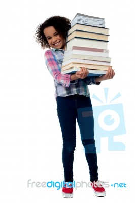 Cheerful Schoolgirl Carrying Pile Of Books Stock Photo