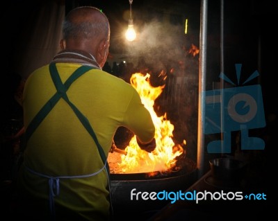 Chef Cook Making A Show With Flames While Cooking In A Night Market Stock Photo