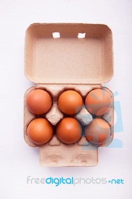Chicken Eggs In Egg Box On White Wooden Background Stock Photo