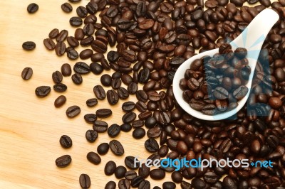 Close Up Of Coffee Beans In White Spoon On Wooden Background Stock Photo