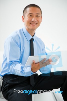 Close-up Of Smiling Businessman Sitting Stairs Holding Digital T… Stock Photo